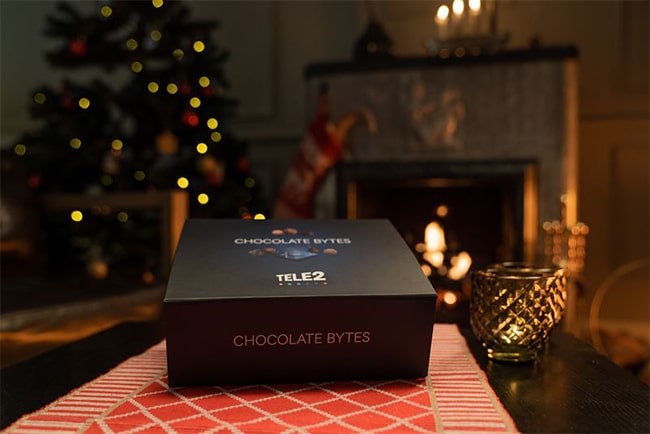 Chokladask står på bord med julgran och öppen spis i bakgrunden.