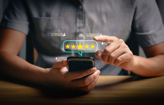 Närbild på man som sitter med mobil med betygskala med stjärnor ovanför skärmen.